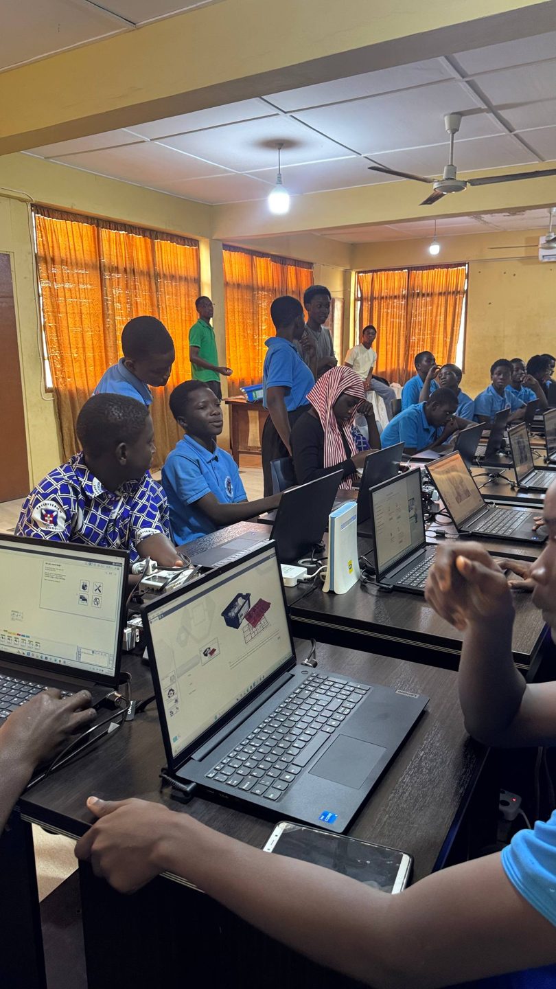 Students programming their robotics kits on laptops during the training